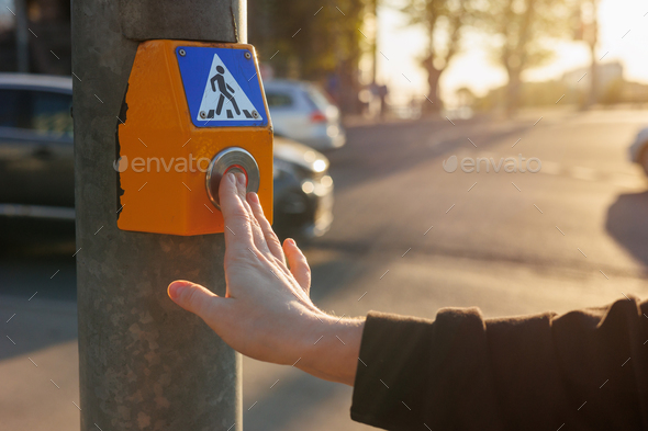 person presses button at traffic light to stop movement of cars and safely cross road intersection - Stock Photo - Images