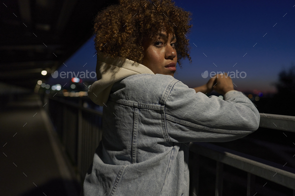 Black woman standing on the bridge at night and looking at camera - Stock Photo - Images