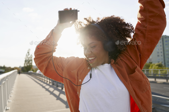 Close up of black woman wearing headphones and dancing on the bridge - Stock Photo - Images