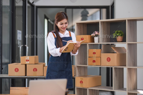 startup small business SME, Entrepreneur happy owner hold book looking at laptop and write customer - Stock Photo - Images