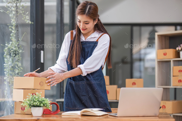 Shipping shopping online ,young start up small business owner writing address on cardboard box at - Stock Photo - Images