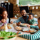 Happy black family talking while eating lunch together at dining table. - PhotoDune Item for Sale
