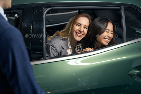 Joyful female lgbt couple on a car review before buying