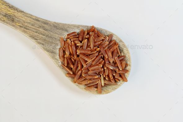 Wooden spoon with whole red rice grains, against white background Stock ...