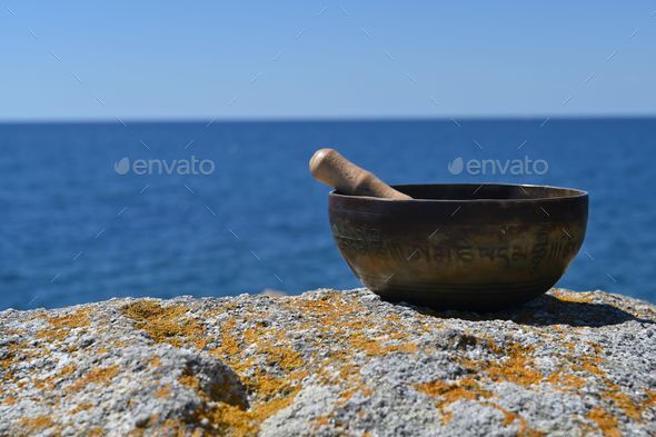 Singing bowl in front of Atlantic ocean. English translation of mantras. transform your impure body