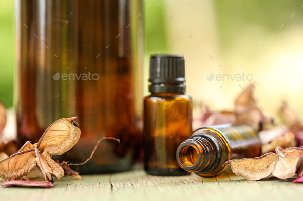 Closeup of bottles of amber essential oil on a wooden fence under the sunlight