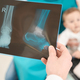 Radiographer examining x-ray of infant lower extremity in two projections - PhotoDune Item for Sale