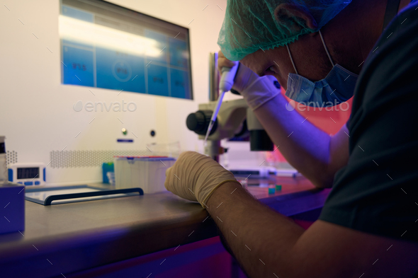 Genetic laboratory worker adding female cells to cell culture dish