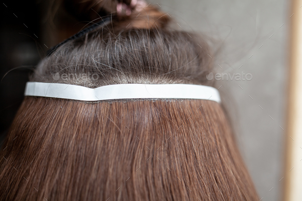 Hair ribbons for extensions on a woman's head at home. Stock Photo
