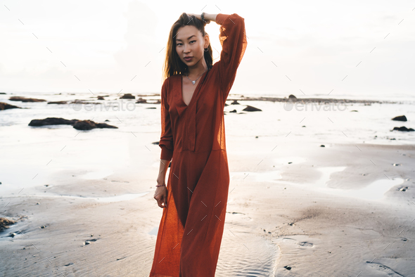 Young model in long light rust colored dress on beach Stock Photo by  GaudiLab