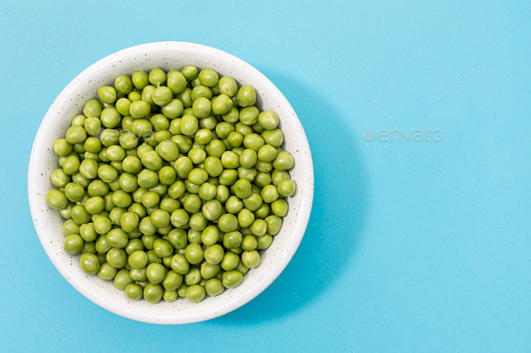 Fresh green peas in bowl isolated on blue background - Stock Photo - Images