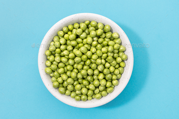 Fresh green peas in bowl isolated on blue background. - Stock Photo - Images
