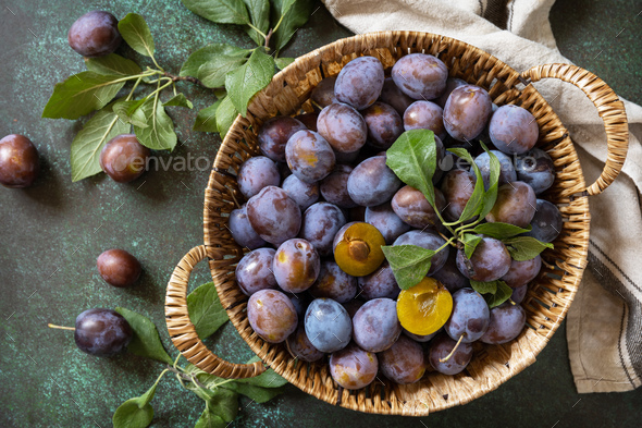 Basket of fresh blue plums on a stone table. View from above. - Stock Photo - Images