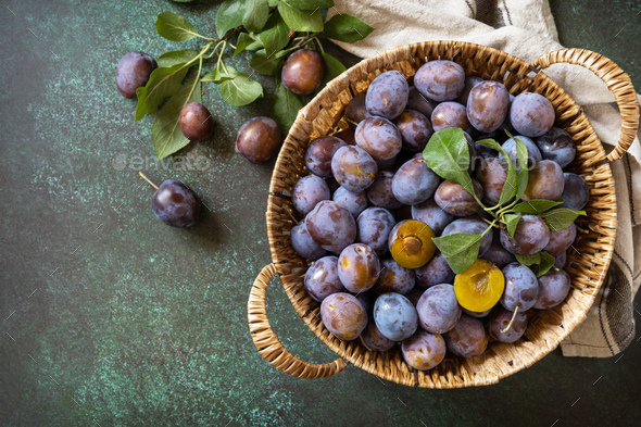 Basket of fresh blue plums on a stone table. View from above. Copy space. - Stock Photo - Images
