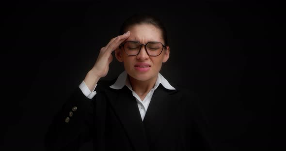 Business Lady in Glasses and a Strict Business Suit Has a Severe Headache