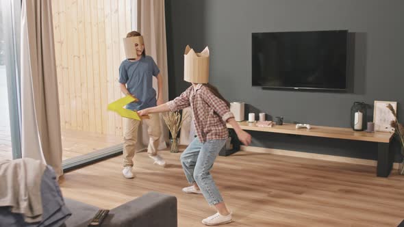 Siblings In Cardboard Helmets Fighting With Toy Swords alt