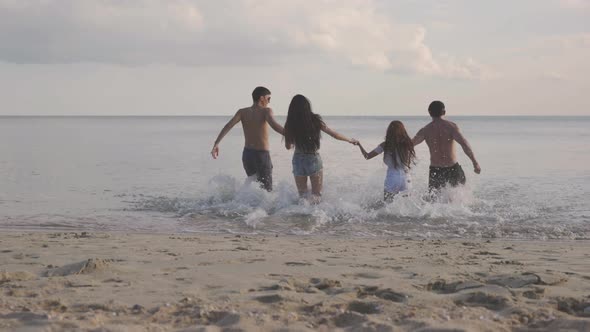 Group of people running to the sea from beach alt
