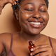 Plus size black woman indulges in skincare ritual applies face serum with beaming smile uses natural - PhotoDune Item for Sale