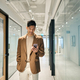 Young happy Asian business man standing in office hallway using phone. - PhotoDune Item for Sale