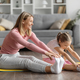 Joyful young mother and little daughter stretching legs together at home - PhotoDune Item for Sale