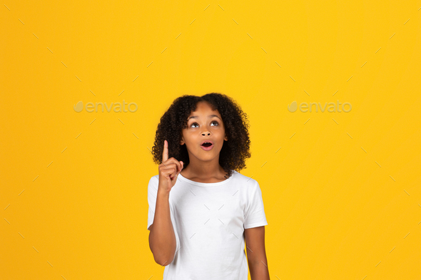 Cheerful shocked adolescent curly african american girl in white t-shirt show finger up, got idea - Stock Photo - Images