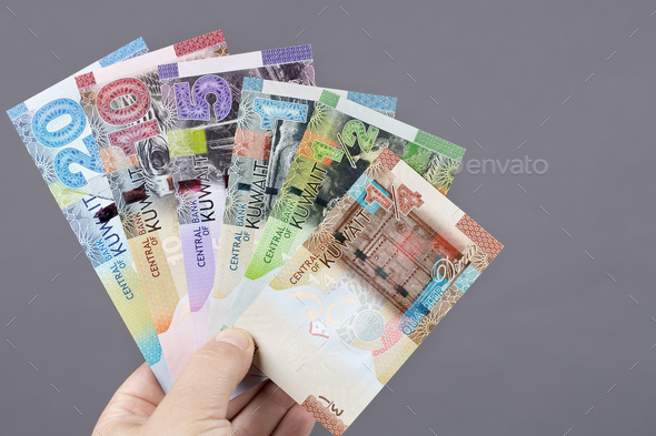 Kuwaiti dinar in the hand on a gray background - Stock Photo - Images
