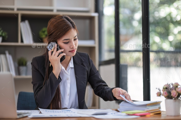 Asian businesswoman in formal suit in office happy and cheerful during using smartphone and working - Stock Photo - Images