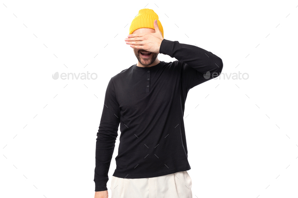 shy young 30 year old guy with a beard dressed in a black jacket and a yellow hat