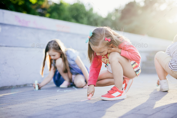 Children drawing on pavement in urban neighborhood - Stock Photo - Images