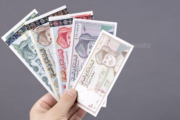 Old Omani money in the hand on a gray background - Stock Photo - Images