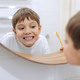 cute 8 years old boy washing face in bathroom looking in mirror and smiling. - PhotoDune Item for Sale