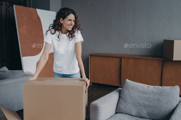 Smiling woman with box preparing for house renovation or relocation, dreaming about modern new home