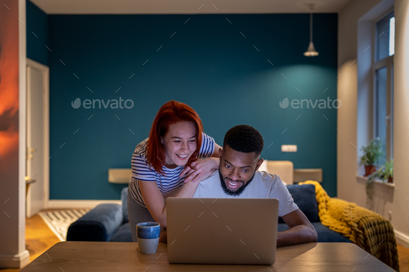 Happy couple reading good news in email on laptop. Glad smiling woman and man show video together - Stock Photo - Images