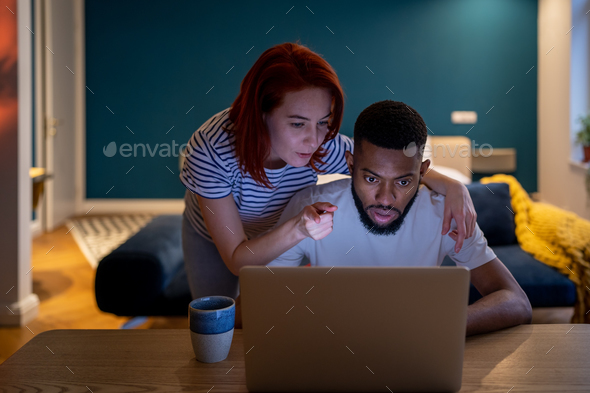 Serious family diverse couple getting ready for big deal working together with laptop in evening. - Stock Photo - Images
