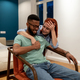 Smiling black man enjoy on armchair communication with hugging european laughing girlfriend at home - PhotoDune Item for Sale