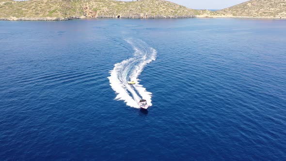 Aerial View of a Motor Boat Towing a Tube. Elounda, Crete, Greece