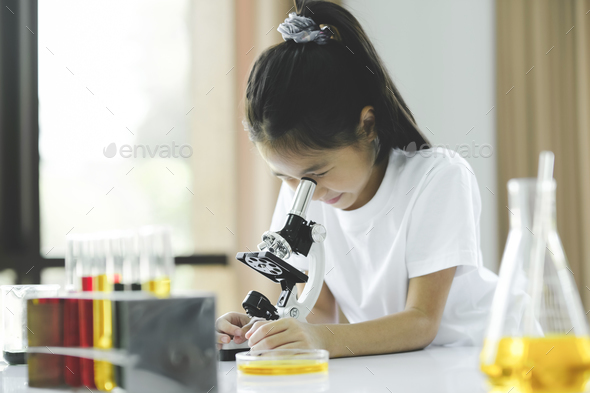 Little child with learning class in school laboratory using microscope - Stock Photo - Images
