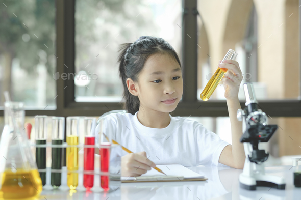 preschool girl is interested in laboratory lesson, taking notes on book for her study. - Stock Photo - Images