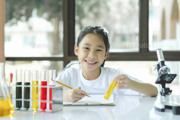 preschool girl is interested in laboratory lesson, taking notes on book for her study. - Stock Photo - Images