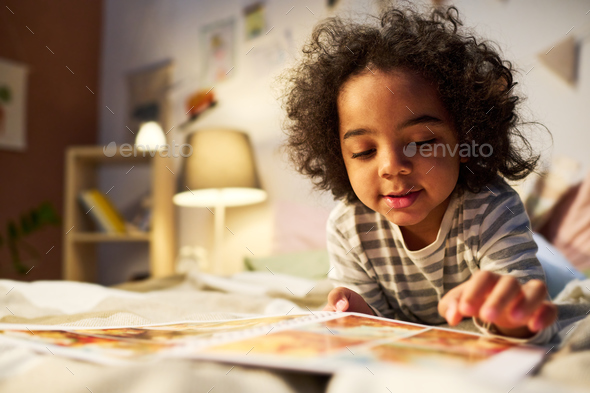 Little boy watching pictures in book - Stock Photo - Images