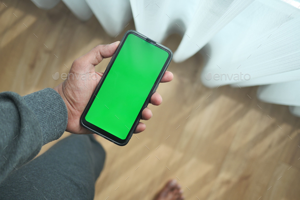  young man hand using smart phone with green screen at home  - Stock Photo - Images