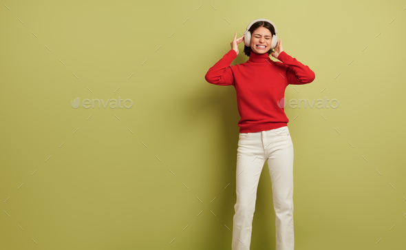 Joyful young lady listening to favorite song and smiling in headphones - Stock Photo - Images