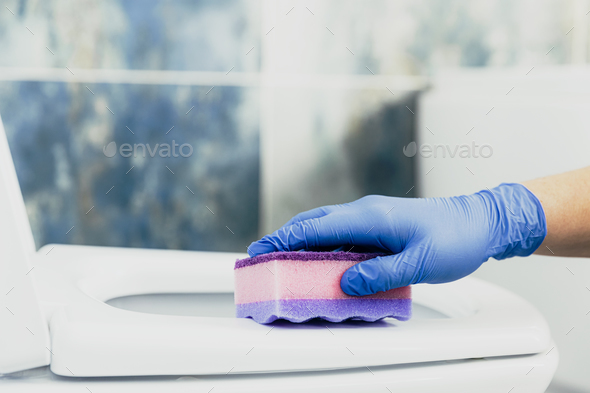 Woman hand cleaning toilet bowl, seat with detergent, pink cloth, wet wipe - Stock Photo - Images