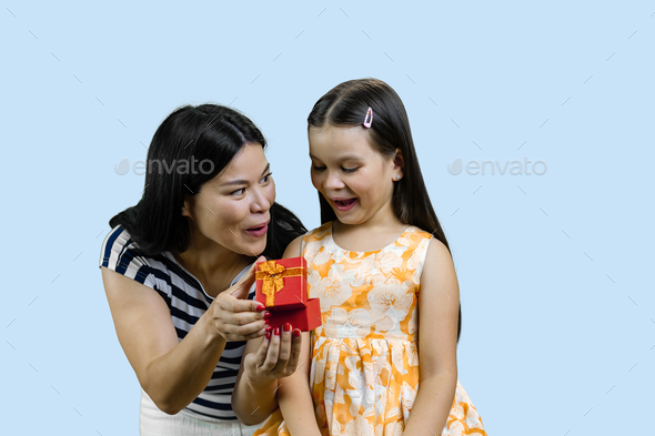 Young brunette lady is giving an opened gift box to her happy little princess. - Stock Photo - Images