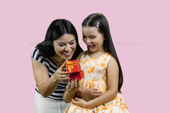 Young brunette mother is opening a red gift box to her happy little princess. - Stock Photo - Images