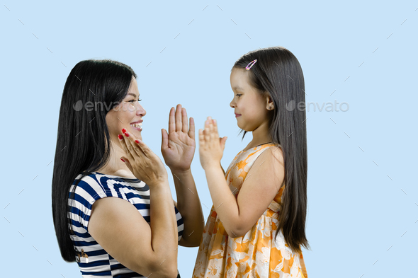 Side view of woman and her daughter are playing clapping game.