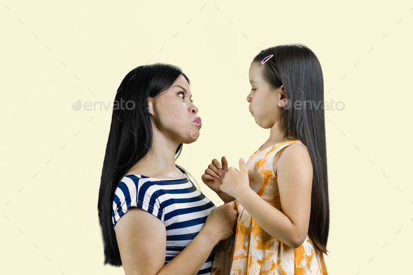 Side view of mother and her little girl are making faces to each other. - Stock Photo - Images