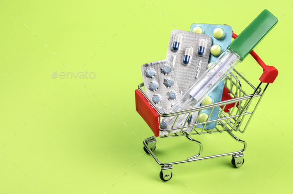 Thermometer, pills, tablets and vitamins in a shopping cart - Stock Photo - Images