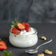 Glass jar of Greek yogurt, nuts and strawberries on grey table with a spoon close up, copy space - PhotoDune Item for Sale