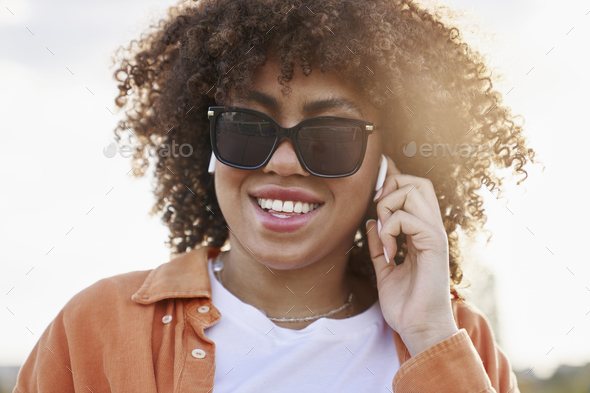 Close up of cheerful black woman in sunglasses and and earphones - Stock Photo - Images